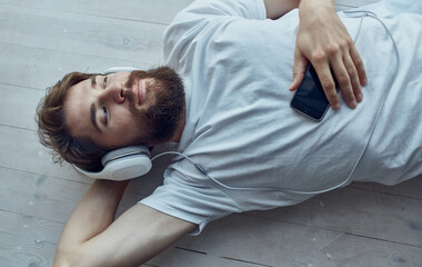 a man lies on a windowsill wearing headphones rest music technology
