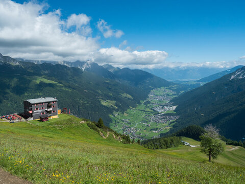 View over green Stubai valley and Neustift im Stubaital village with Elferhutte, grass meadow, moutain peaks and kites. Tirol Alps, Austria, Summer blue sky, white clouds