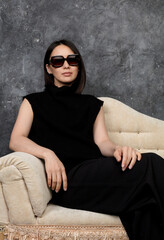 Beautiful korean woman dressed in black dress sitting on sofa