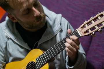man playing ukulele at home