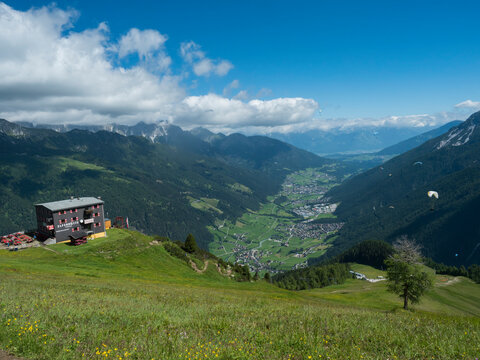 View over green Stubai valley and Neustift im Stubaital village with Elferhutte, grass meadow, moutain peaks and kites. Tirol Alps, Austria, Summer blue sky, white clouds