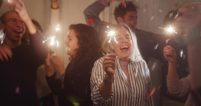 A multi-ethnic group of friends celebrating the holidays at a home party, atmosphere joy and happiness, people laughing and smiling, birthday celebration concept, sparklers and sparks