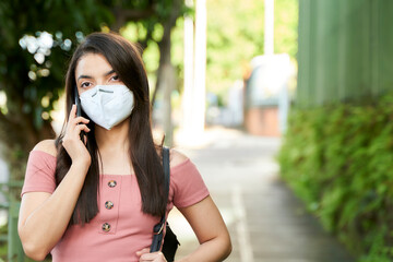 Impatient young woman wearing face mask talking on smart phone in the street