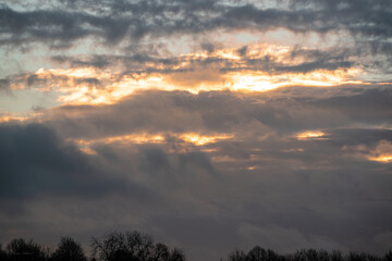 sun peeping out from behind big illuminated clouds