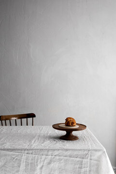 Butter croissant placed on a wooden cake stand on a table with chair in the background 