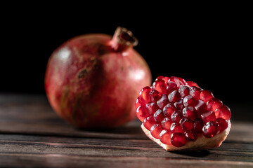 Craked ripe pomegranate on dark wooden background