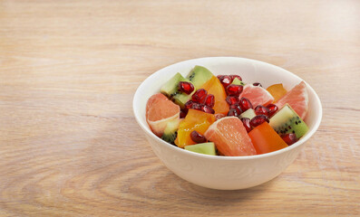 Fruit salad in a white bowl on a wooden table
