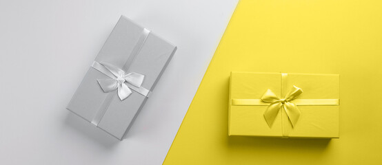 Two gift boxes on gray yellow background. Two-color background. Concept of color year. Banner image