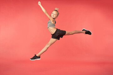 Adorable little gymnast jumping and doing splits in the air