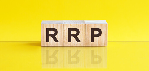 RRP - Recommended Retail Price - word is made of wooden building blocks lying on the yellow table