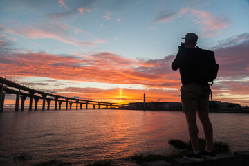 Fototapeta premium Silhouette of man making photo of highway bridge in sunset time