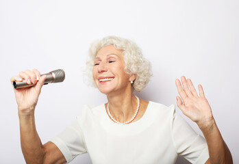 Happy old woman holding a microphone and singing isolated