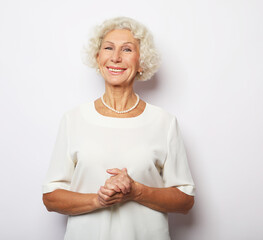 Cheerful elderly woman standign on white background