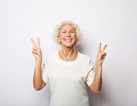 good mood happy smiling positive old woman show v-sign isolated over white background