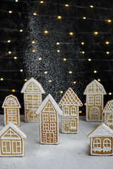 Fototapeta na wymiar Gingerbread houses on the background of garland lights. New Year's traditional treats. Glazed Christmas cookies.