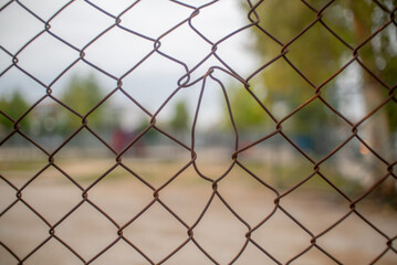 View of empty playground through a rusty wired fence