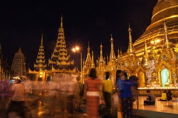Fototapeta premium a group of people standing in front of a lit up building at night