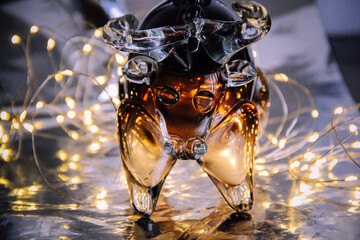 Close-up of a dark brown glass bull on a background of silver foil and flashlights 