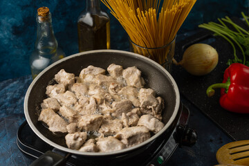 Macro shot view of frying pan with fragrant grilled meat on the stove on ingredients for cooking background. Food concept. Homemade meal. Traditional recipe. Cookbook illustration.