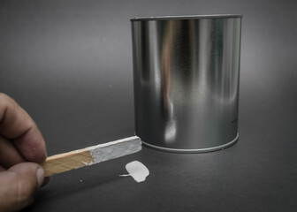 can of white paint, stirring with palette, top view black background.