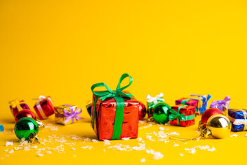 Gift box with a Christmas present on a yellow background, among the New Year's decorations