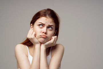 emotional woman who has acne on her face on a gray background health problems