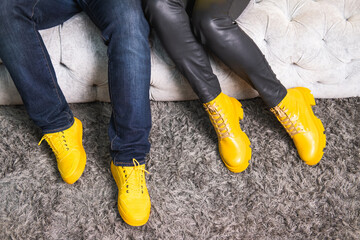 Demonstrating trendy colors 2021 - Gray and Yellow. Couple in similar clothes sitting on the sofa.
