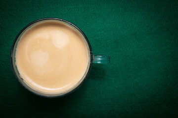 Top view of a cup of coffee on a green background. Coffee drinking concept.