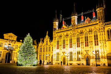 Fototapeta na wymiar Christmas tree on Burg square and City Hall in Bruges, Belgium. Festive lights and decorations.