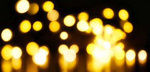 Spirituelle Weihnachtliche Beleuchtung in Form eines gelben Bokehs auf einem schwarzen Hintergrund. Magisches Licht.