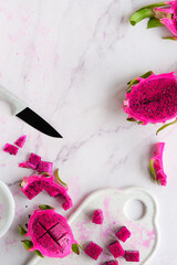 Ugly food. Juicy pink dragon fruit, pitaya, pitahaya sliced on marble table. Trendy top view with...