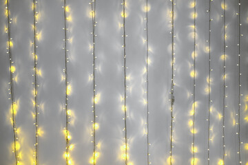 Demonstrating trendy colors 2021 - Gray and Yellow. Shiny light garlands hanging on grey wall and...