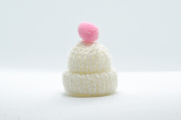 Warm winter white hat with a pink decoration. Minimal concept 