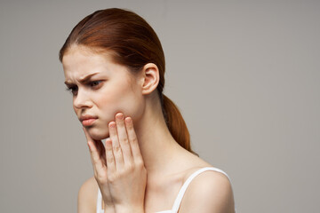 beautiful woman touching face with hand toothache red hair white t-shirt