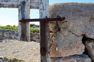 detail of iron latch on typical wooden door, with lichens, on stone wall next to the path, with beautiful blue sky over Mediterranean forest, mallorca spain