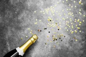 Champagne bottle and confetti stars on ultra violet background. Christmas, birthday, carnival concept.