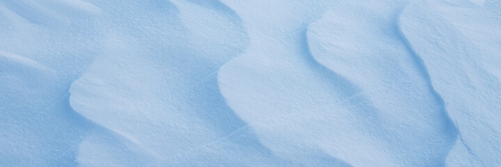 Obraz premium Beautiful winter background with snowy ground. Natural snow texture. Wind sculpted patterns on snow surface. Wide panoramic texture for background and design.