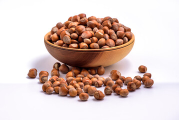 Hazelnuts in a wooden bowl on white background. Solid ripe Hazelnuts
