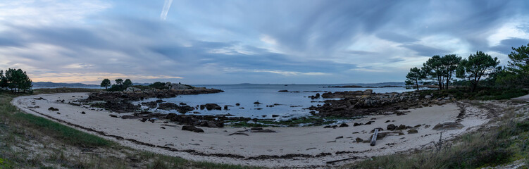 Fototapeta na wymiar panorama view of a beach at low tide under an overcast night sky with daybreak and colorful sunrise