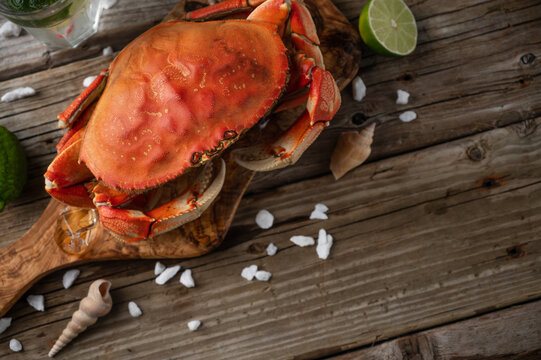 Appetizing cooked crab on wooden board background with lime and seashells. Delicious meal. Seafood concept. View from above. Space for text. Flat lay.