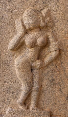 Fototapeta na wymiar Hampi, Karnataka, India - November 4, 2013: Ruinous Kadelekalu Ganesha temple. Closeup of brown stone mural sculpture of dancing woman.
