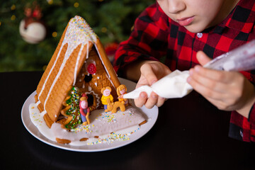 A boy decorating Christmas gingerbread house