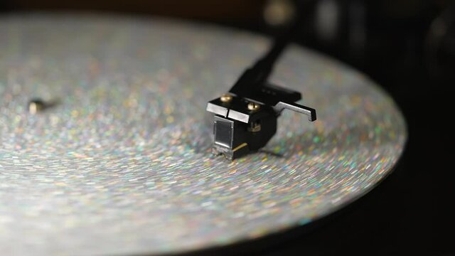Footage of vintage-styled record player spinning vinyl silver sequins record. Cinemagraph. Side view. Analog audio equipment, sound concept.