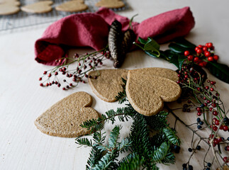 Arrangement of holiday objects and decorations -- green spruce, red berries, ginger heart cookies.
