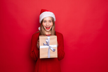 Beautiful woman holding large wrapped giftbox isolated red background