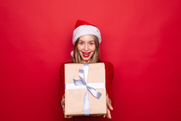 Beautiful woman holding large wrapped giftbox isolated red background