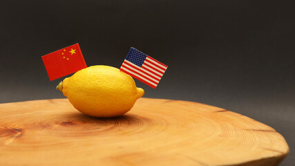 American & Chinese flags poking out of a lemon on a chopping block representing the strained soured relationship and trade war. Foreign policy and international relations