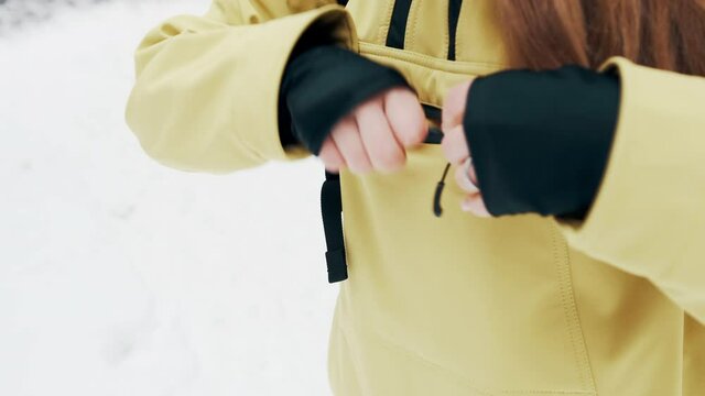 Girl puts the phone in the pocket of a yellow jacket in winter