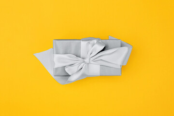 Gift with background in trending colors of 2021 - gray and yellow.