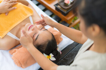Obraz na płótnie Canvas Asia female enjoy Thai facial spa massaging in the garden.